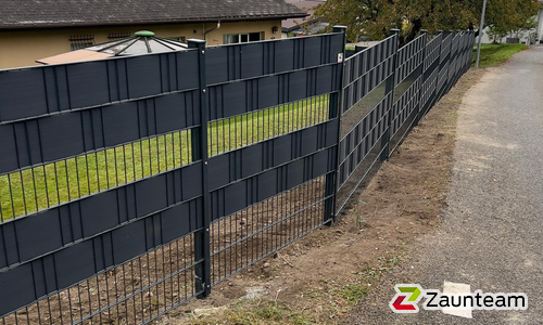 Doppelstabmatten schwer feuerverzinkt und anthrazit beschichtet mit Pfosten 60 x 40 mit Abdeckleisten einbetoniert wurde in Muraz von Zaunteam Wallis, Niedergesteln im Jahr 2025 erstellt.